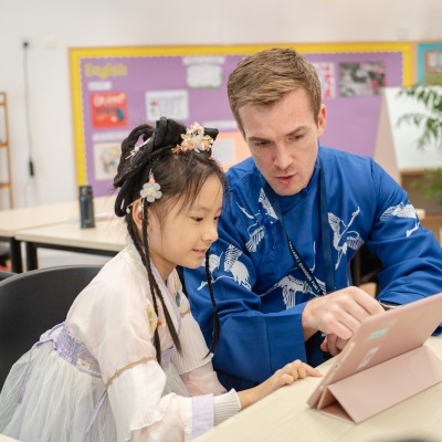 Student and teacher working with laptop